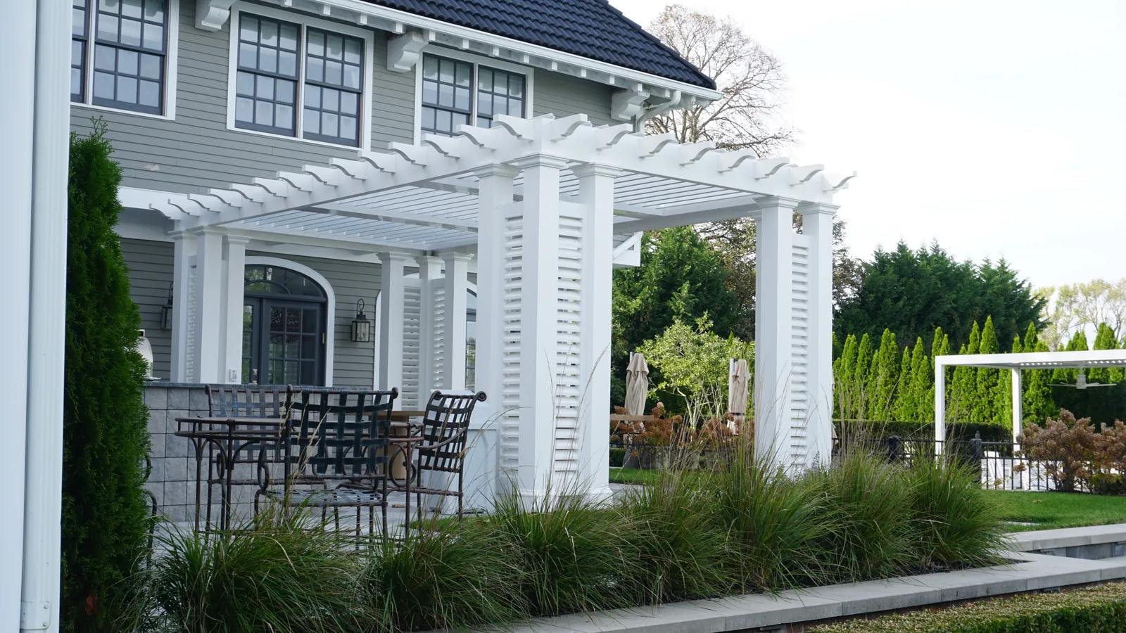 Pergola and dining terrace beside the house, edged with ornamental grasses