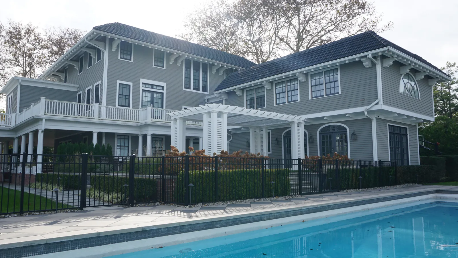 Pool and fenced terrace below the house, with the pergola at the center