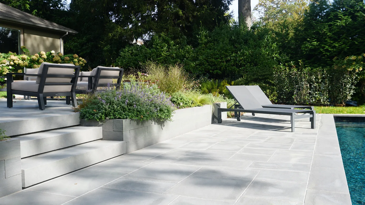 Stone pool terrace with lounge chairs, stepped planters and hydrangeas